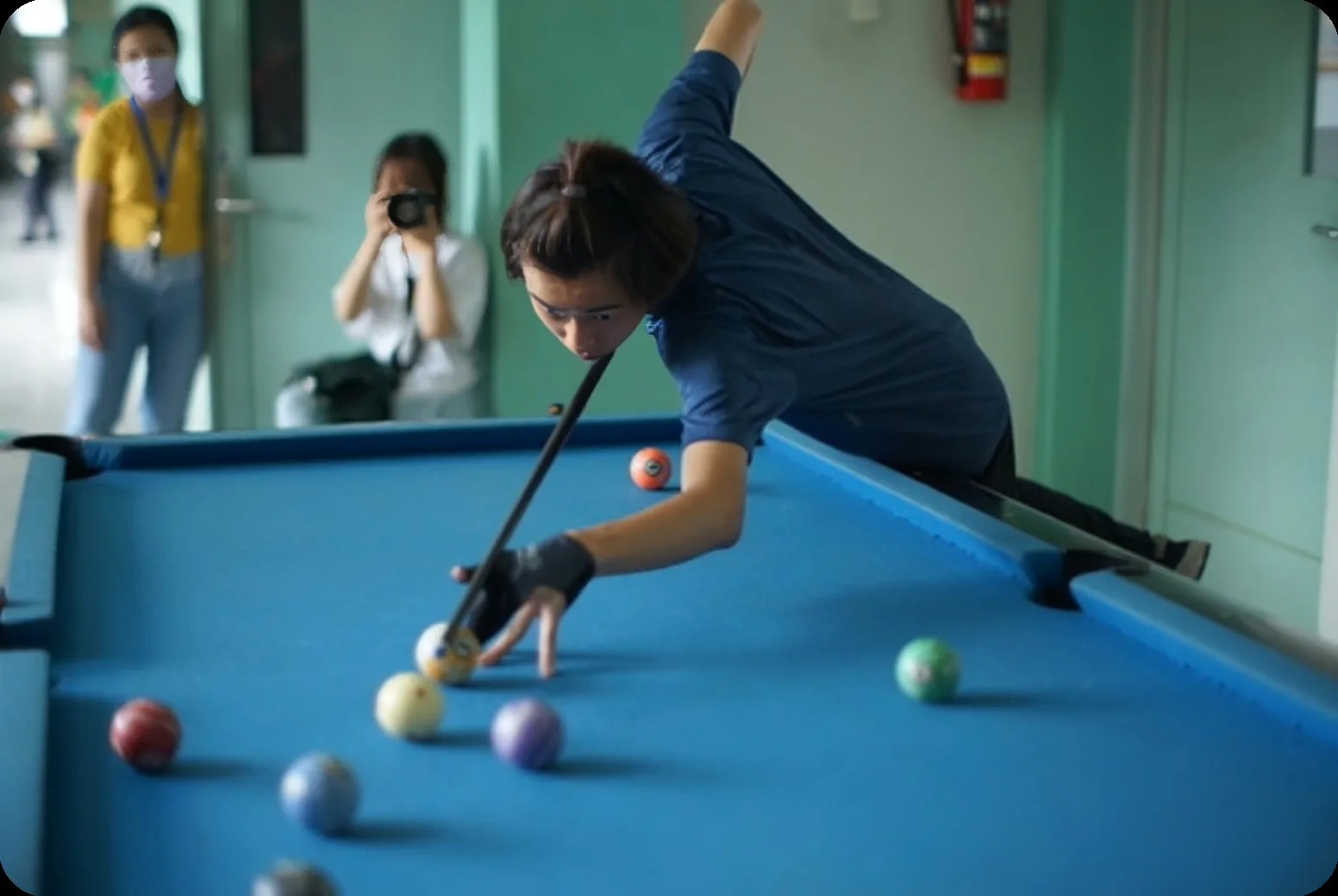 A student lining up a shot on a blue billiard table