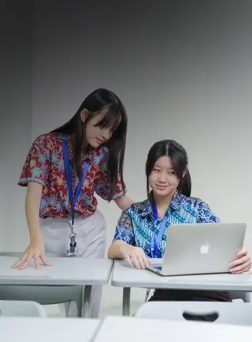 Two students reviewing photos on a laptop in the studio